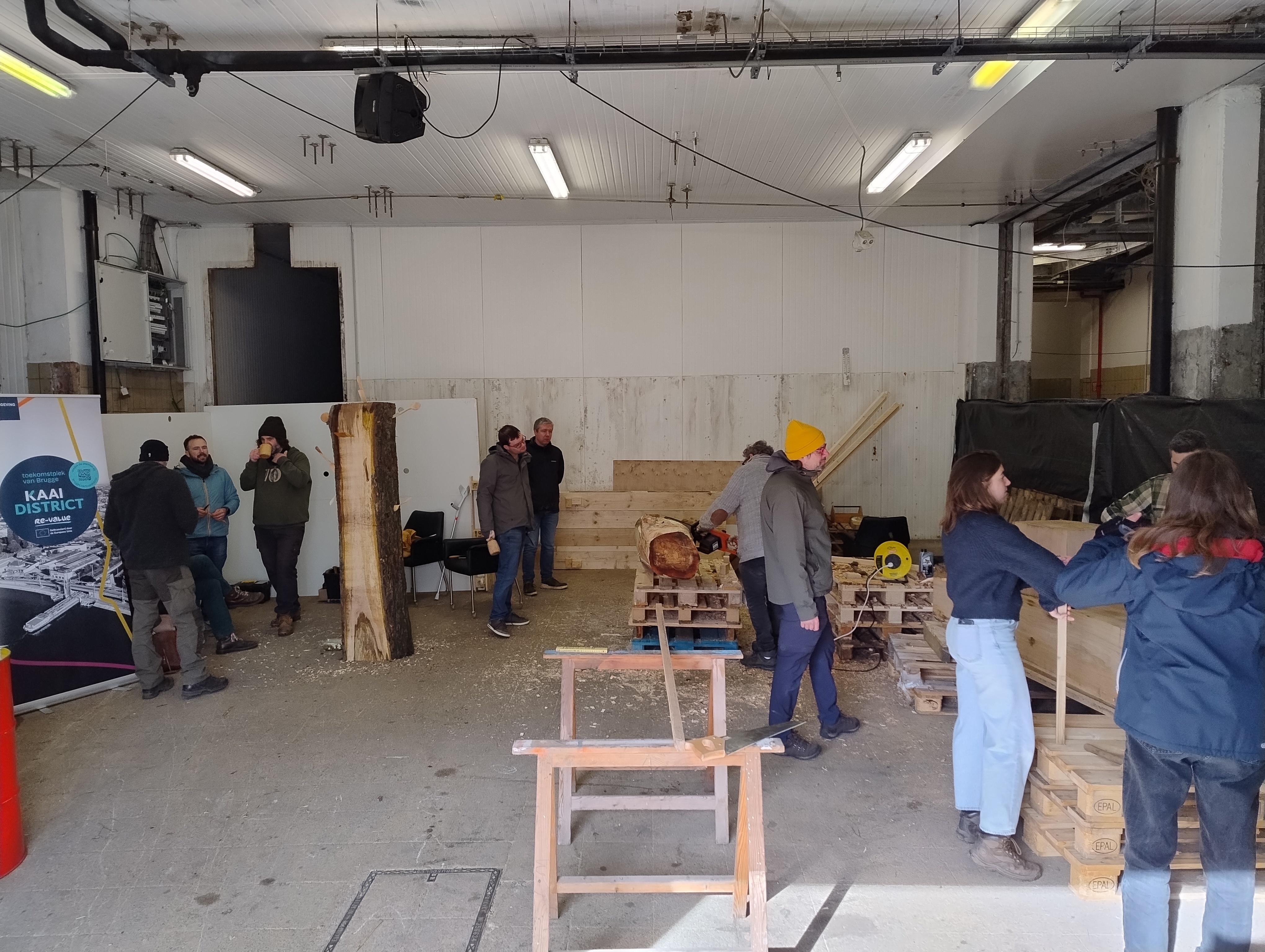 A group of people are doing various things in what looks like a workshop