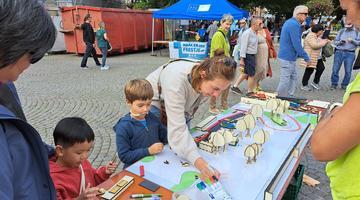 A photo of some children and a grown up engaging on a desk with cardboard trees
