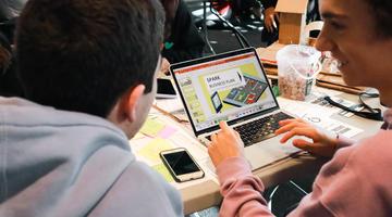 Two people collaborating around a laptop