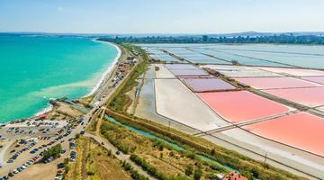 A picture from above of the Wetlands in Burgas. the image shows the Black Sea on the left and wetlands on the right, with small strip of land separating the two.