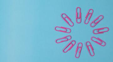 Composition of pink paper clips isolated on blue background