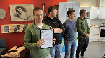 Four young people with the person in front holding up a diploma, presumingly for having had the best idea. 