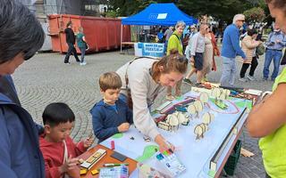A photo of some children and a grown up engaging on a desk with cardboard trees