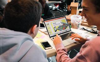 Two people collaborating around a laptop