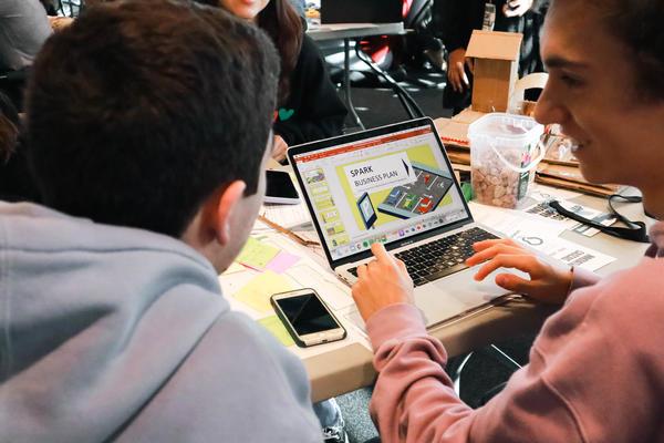 Two people collaborating around a laptop