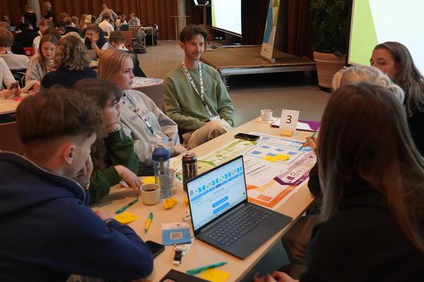 A group of young people engaged in conversation around a table. 