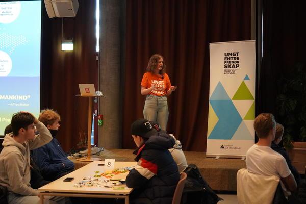 A person on stage wearing a shirt saying Ungt Entrepenorskab, which translates into Young entrepeneurship 