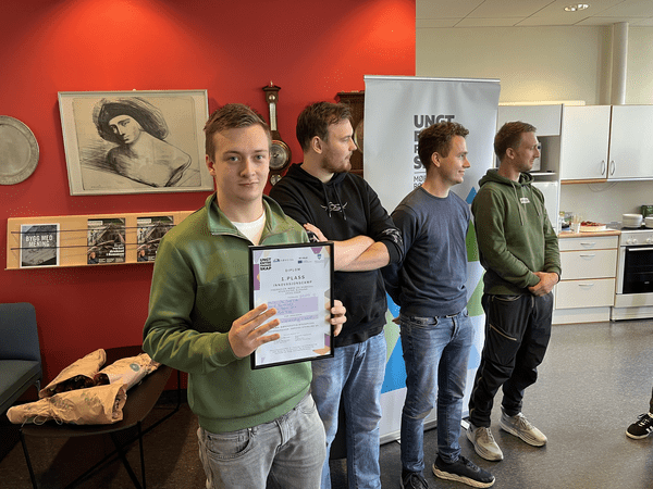 Four young people with the person in front holding up a diploma, presumingly for having had the best idea.